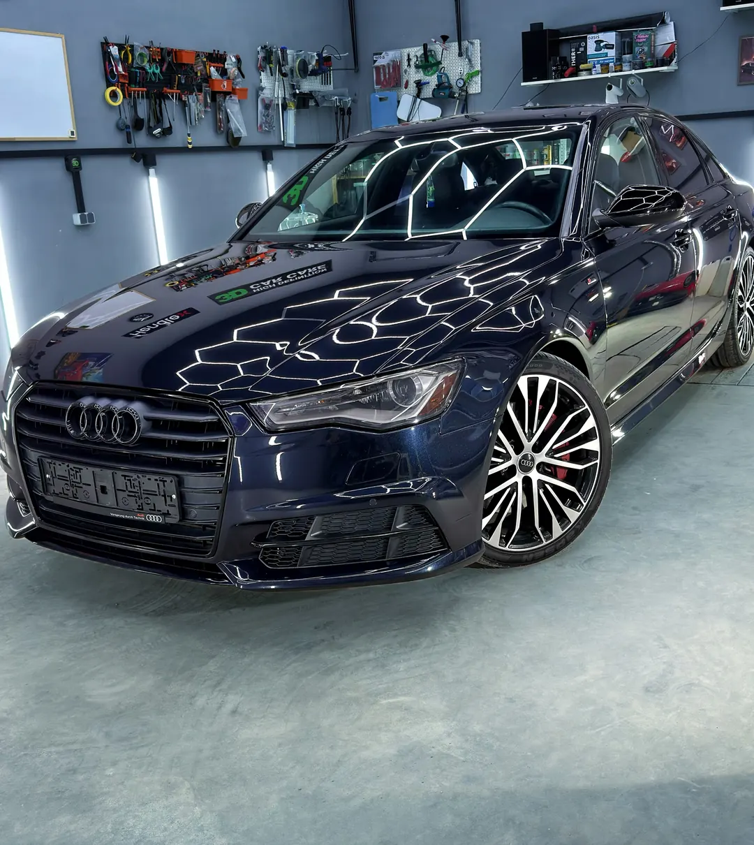 Тёмно-синяя Audi A6 в боксе: белые линии света на капоте и лобовом стекле
