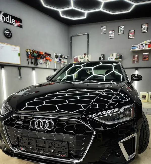 Чёрная Audi в боксе, на капоте белые линии света