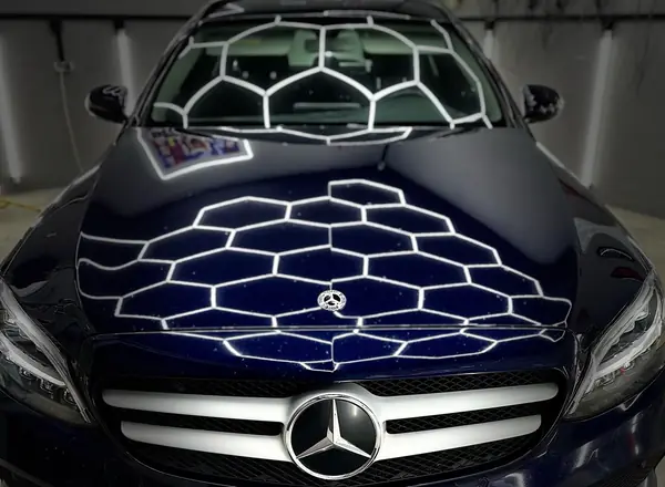 Тёмно-синий Mercedes C-класса анфас, на капоте белые линии света
